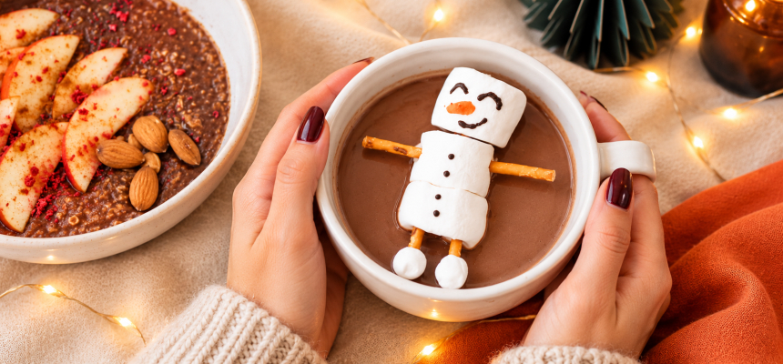 Ženské ruce drží hrnek kakaa se sněhulákem z marshmallow